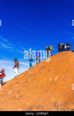 I turisti si arrampicano sul ripido terreno ondulato sulla cima di Uluru. Northern Territory, Australia Foto Stock