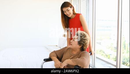 Donna allegra avendo cura di sua nonna in carrozzella Foto Stock