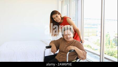 Donna allegra avendo cura di sua nonna in carrozzella Foto Stock
