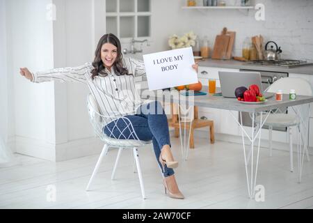 Donna dai capelli scuri in una blusa a righe che guarda felice Foto Stock