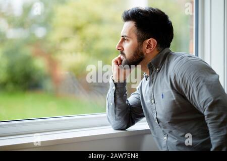 Uomo che guarda fuori della finestra Foto Stock