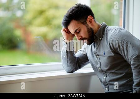 Uomo che guarda fuori della finestra Foto Stock