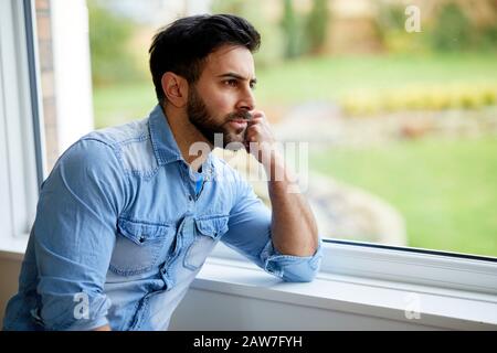 Uomo che guarda fuori della finestra Foto Stock