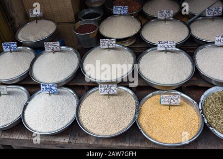 Diversi tipi di riso in ciotole per la vendita sul mercato agricolo in Vietnam. Esposizione di stallo di cibo di strada Foto Stock