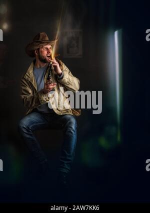 Immagine comica. Cowboy ubriaco in un cappello a testa larga brimmata spara aria da un revolver in un salone affumicato Foto Stock