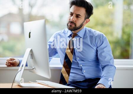 Uomo seduto al computer pensieroso