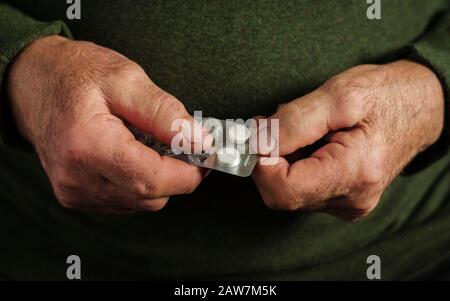 Uomo anziano che prende una compressa da una confezione blister Foto Stock
