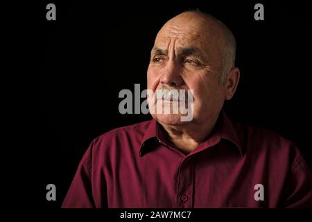Uomo anziano solitario seduto reminiscing, espressione nostalgica. Foto Stock