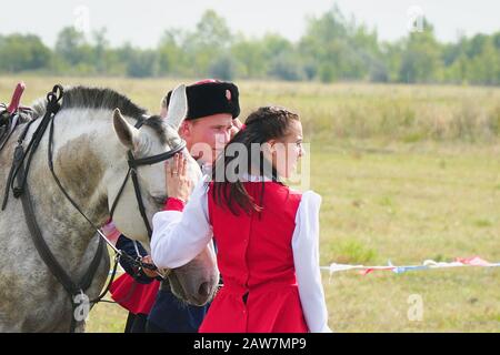 Samara , Russia - 17 agosto 2019: Giovane Cossack e ragazza Cossack in costumi nazionali in piedi accanto al cavallo. La ragazza dice addio al Cossac Foto Stock