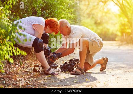 Coppia di anziani che pratica il pattinaggio in linea in estate Foto Stock