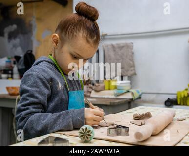 Una ragazza di 6 anni fa il suo mestiere di argilla - un cuore come un dono per la mamma, master class in un laboratorio di ceramica Foto Stock