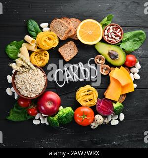 Alimenti ricchi di carboidrati: Pane, pasta, avocado, farina, zucca, broccoli, fagioli, spinaci. Il concetto di mangiare sano. Su sfondo nero. Foto Stock