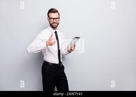 Ritratto di sicuro positivo leader uomo freelancer utilizzare tablet mostra pollice su segno approvare associazione indossare pantaloni bianchi neri pantaloni isolati Foto Stock