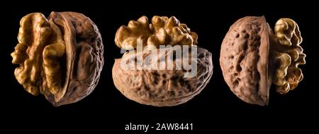 Set di noci a metà apertura con kernel isolato su sfondo nero Foto Stock