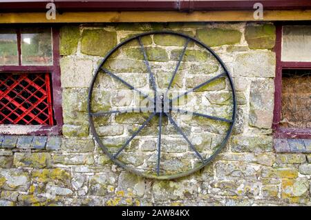 Una vecchia ruota del carrello montata su una parete in una fattoria vicino a Newbridge-on-Wye, Powys, Galles. Foto Stock