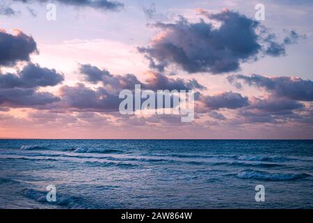 Immagine panoramica del cielo viola drammatico al tramonto con nuvole sul mare. Foto Stock