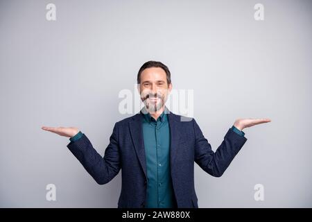Foto di bel direttore di vendita uomo che consiglia tenere due prodotti su braccia aperte scegliere una camicia migliore abbigliamento blazer plaid tuta blu isolato Foto Stock