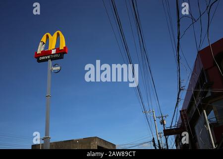 McDonald's esterno nelle Filippine con un segno che è stato danneggiato da un tifone Foto Stock