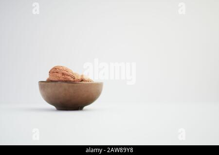 Noci (Juglans Regia) in una ciotola color bronzo su sfondo bianco Foto Stock