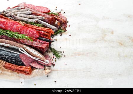 Assortimento di salumi secchi e salsicce affumicate su sfondo bianco di legno. Vista dall'alto. Spazio libero per il testo. Foto Stock