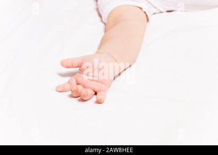 Clouse-up foto di piccolo bambino mano che si posa sul foglio del letto Foto Stock