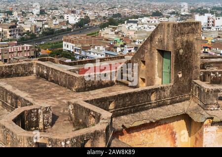 Rovine sul tetto di antico complesso di abitazione e vista della città dall'interno porta di Galta verso il tempio del sole in giorno estivo luminoso a Jaipur, Rajasthan, India Foto Stock