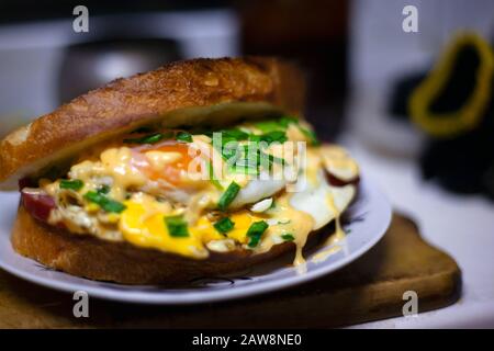 panino arrosto con salsiccia, uova, formaggio e cipolle verdi. panino con doppio pane tostato succoso. Foto Stock