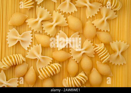 Maccheroni closeup vista dall'alto. Il disco di pasta di diverse forme, archi, spirali e gusci su uno sfondo di spaghetti. La pasta. Foto Stock