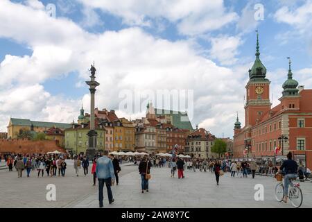 Turisti che camminano attraverso Piazza del Castello a Varsavia, Polonia con La Colonna di Sigismund e il Castello reale Foto Stock