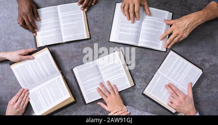 Vista in elevazione del popolo santo di lettura di libri su sfondo di legno Foto Stock