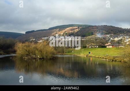 Clydach vale nella Rhondda Valley, nel Galles meridionale, con lo Stagno Inferiore o il lago inferiore in primo piano. Passeggiata popolare locale intorno al lago con i loro cani Foto Stock