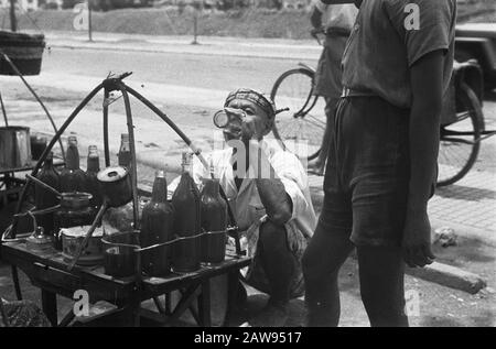 Uomo bere vetro al venditore di strada della limonata? Date: 01/01/1947 Location: Indonesia Dutch East Indies Foto Stock