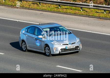 Taxi 2015 Silver Toyota Prius T3 VVT-i CVT; traffico veicolare nel Regno Unito, trasporto, veicoli elettrici moderni, motore elettrico, EV, proprietà di auto elettriche a batteria, berline ibride ad alte prestazioni alimentate elettricamente, sull'autostrada M61. REGNO UNITO Foto Stock