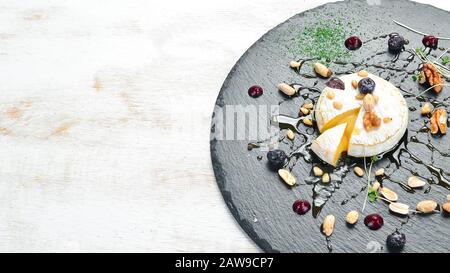Camembert formaggio alla griglia con miele e noci. Vista dall'alto. Spazio libero per il testo. Stile rustico. Foto Stock