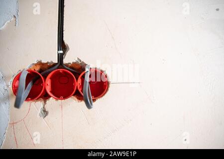 Lavori elettrici con finitura ruvida, l'elettricista collega e monta fili di rame per la presa in appartamento. Foto Stock