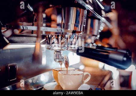 Primo piano Processo di preparazione di bevande calde su macchina professionale per caffè carruba. L'espresso si versa in due tazze Foto Stock