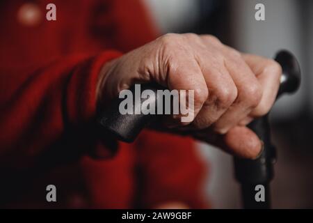 Mani di vecchia donna che tiene la canna, la pelle rugosa. Foto Stock