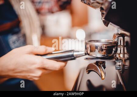 I baristi delle mani trattengono una macinatura fine del caffè per espresso. Concetto processo di produzione di bevande. Foto Stock