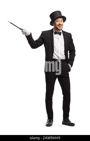 Ritratto a tutta lunghezza di un mago sorridente felice che punta con una bacchetta magica isolata su sfondo bianco Foto Stock