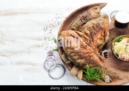 Pesce di carpa fritto in un piatto di legno. Piatti di pesce. Vista dall'alto, spazio libero per il testo. Stile rustico. Foto Stock