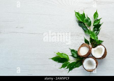 Cosmetici a base di cocco e foglie tropicali. Su uno sfondo di legno bianco. Disposizione piatta. Foto Stock
