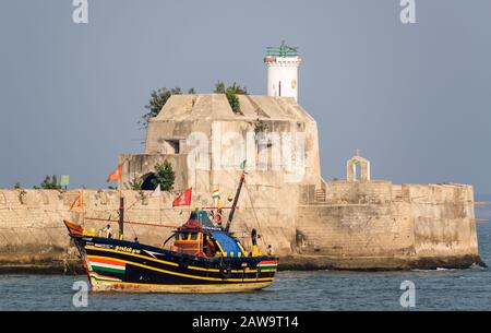 Una colorata barca da pesca passa davanti al Pani Kotha aka Fortim De Mar, la fortezza dell'isola e la prigione in mezzo al mare, al largo dell'isola di Diu. Foto Stock