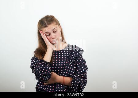 ragazza in un abito nero con cerchi bianchi ragazza sconvolta mette la testa sulla mano pensa Foto Stock