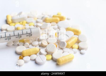 Un mazzo di compresse gialle e bianche, pillole con siringa. Foto Stock