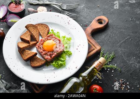 Tartaro di vitello con tuorlo d'uovo e pane nero. Vista dall'alto. Spazio libero per il testo. Foto Stock