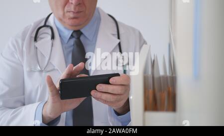 Immagine con un'immagine di Doctor Texting su Cellphone nell'armadio dell'ospedale Foto Stock