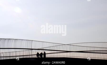 Silhouette di coppia a piedi con passeggino sul ponte pedonale contro il cielo blu. Izmir, Turchia. Foto Stock