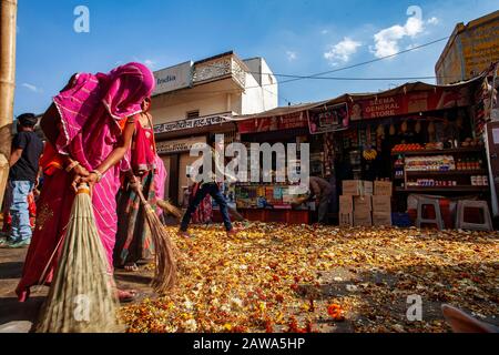 Pushkar in Rajasthan, India, 13 febbraio 2018: Donne indiane che puliscono via Pushkar dai fiori festosi Foto Stock