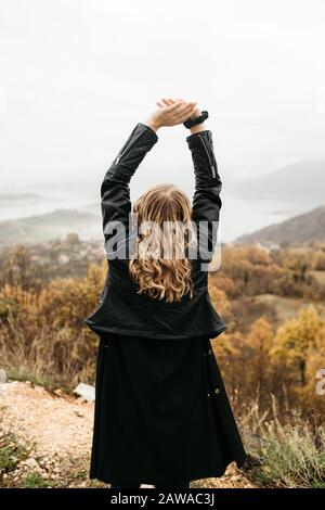 ragazza felice con capelli ricci biondi danze solo su un lago, i suoi capelli sta volando a causa del vento flusso, libero come un uccello. foto di ragazza con capelli ricci Foto Stock