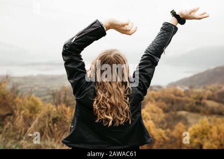 ragazza felice con capelli ricci biondi danze solo su un lago, i suoi capelli sta volando a causa del vento flusso, libero come un uccello. foto di ragazza con capelli ricci Foto Stock